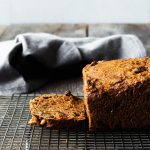 rosemary bread on a cooling rack with a slice cut off and a linen towel in the background.
