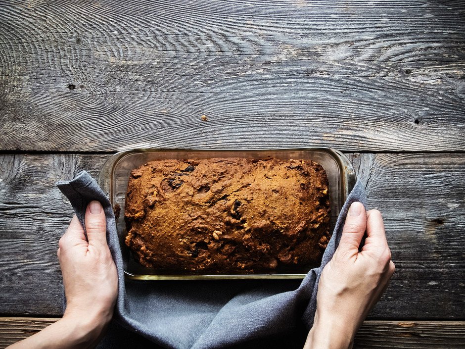 an overhead image a two hands holding a rosemary bread pan with a blue linen.