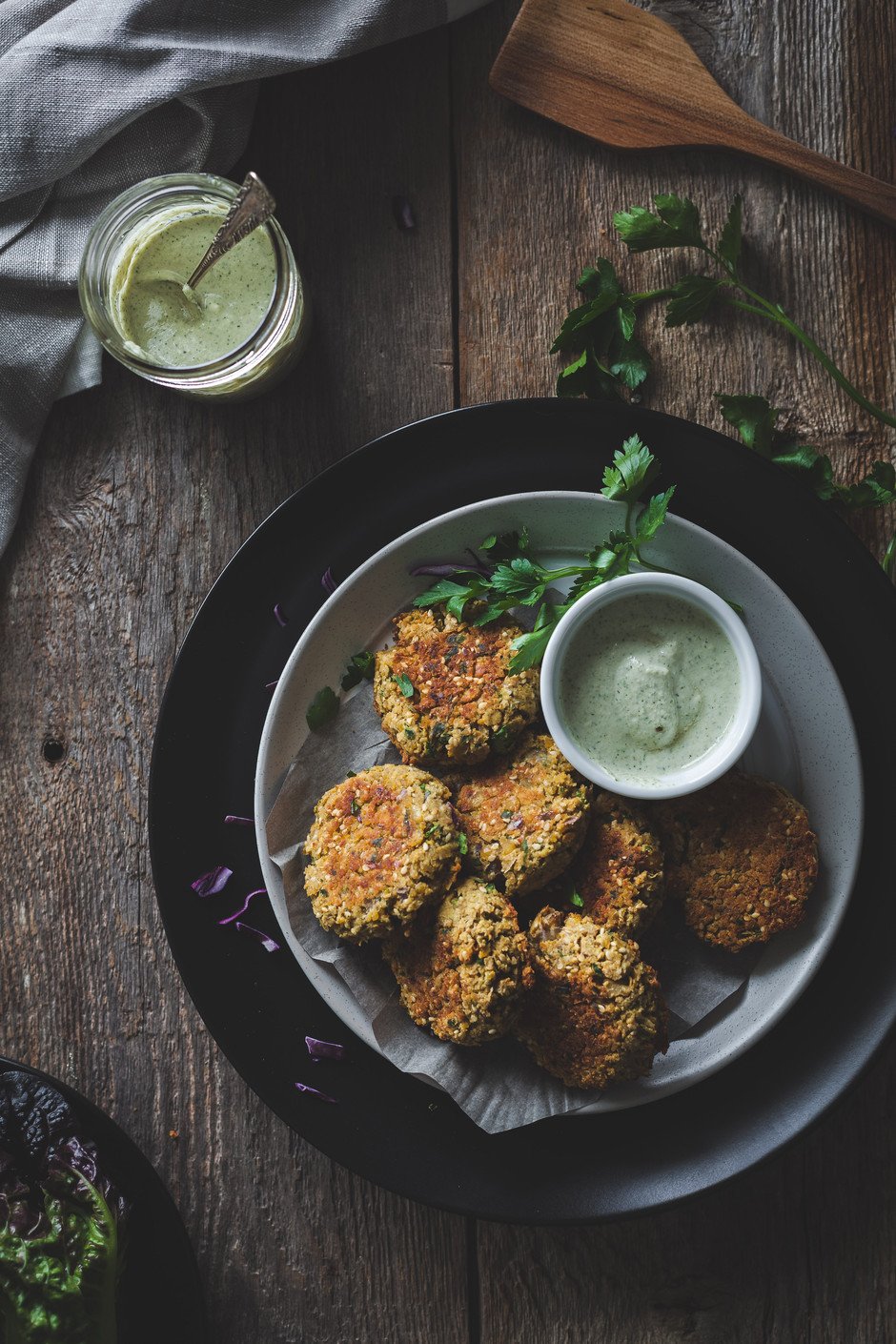 overhead view of falafels and dip on a black plate with parsley.