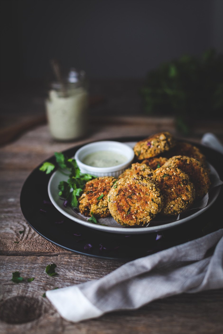 a portrait of falafels and dip on a black plate.