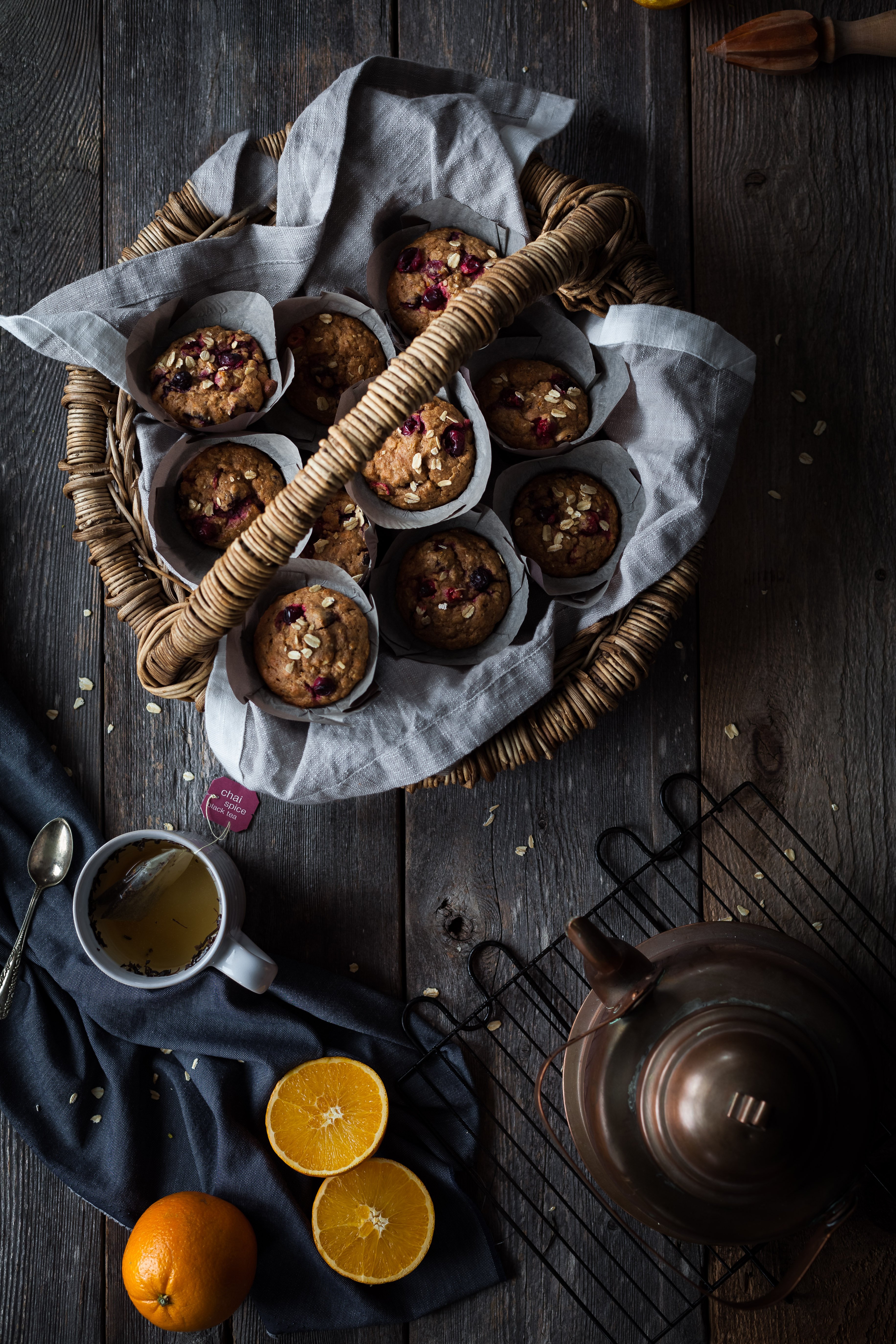 an overhead image of vegan cranberry orange muffins in a basket with a mug of tea.