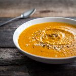 a head on image of a bowl of Sweet Potato Soup on a wood surface.