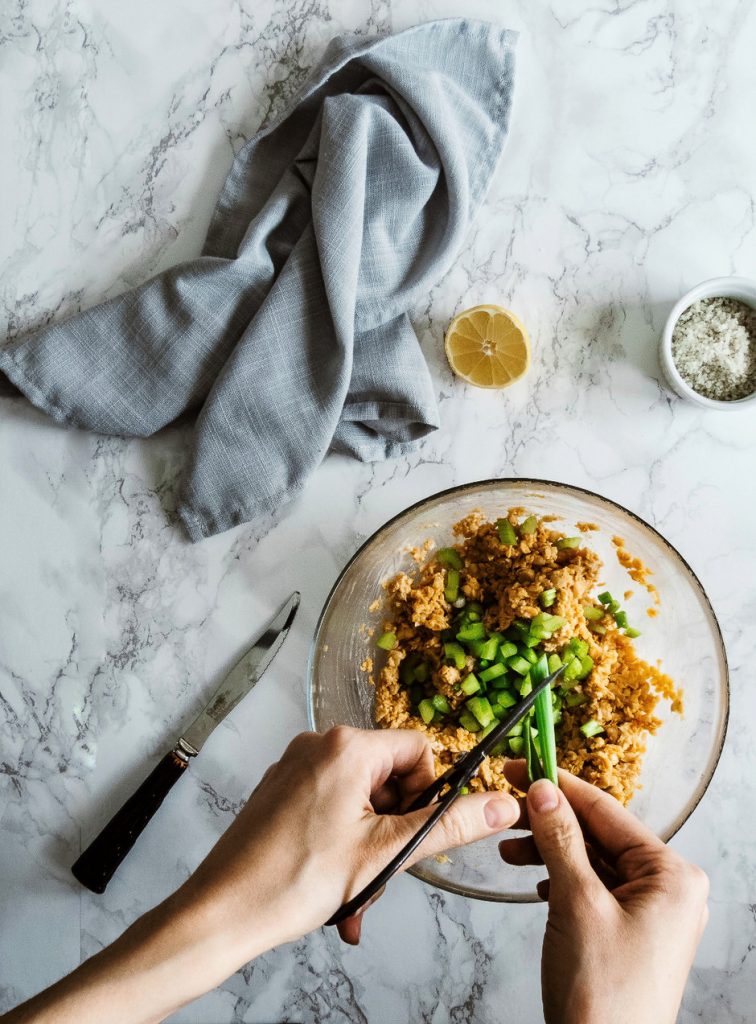 a cook chopping herbs into a bowl of chickpeas.