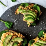 overhead of three chickpea sandwhcihes on a slate board with spinach and salt.