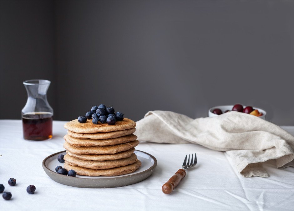 a stack of vegan spelt pancakes with blueberries on top.
