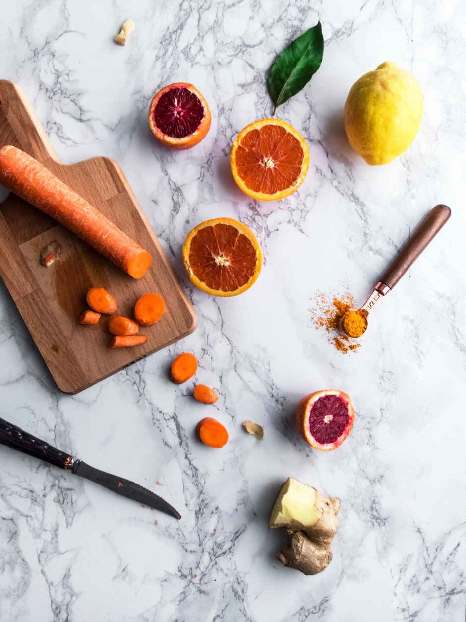 Overhead image of a cutting board, knife, carrots and orange slices.
