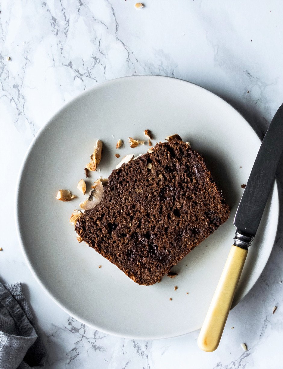 overhead image of a slice of Double Chocolate Banana Bread on a white plate on a marble surface.