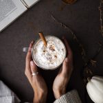 over head image of hands cupping pumpkin spice latte.