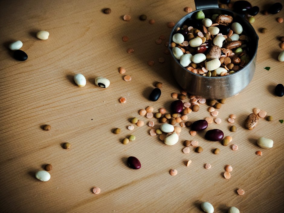 a close up image of a mix of dried beans in a measuring cup.