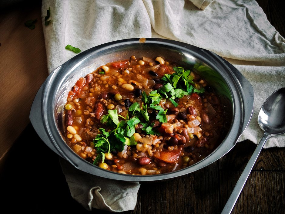 a closeup shot of seven bean soup on a wooden surface.