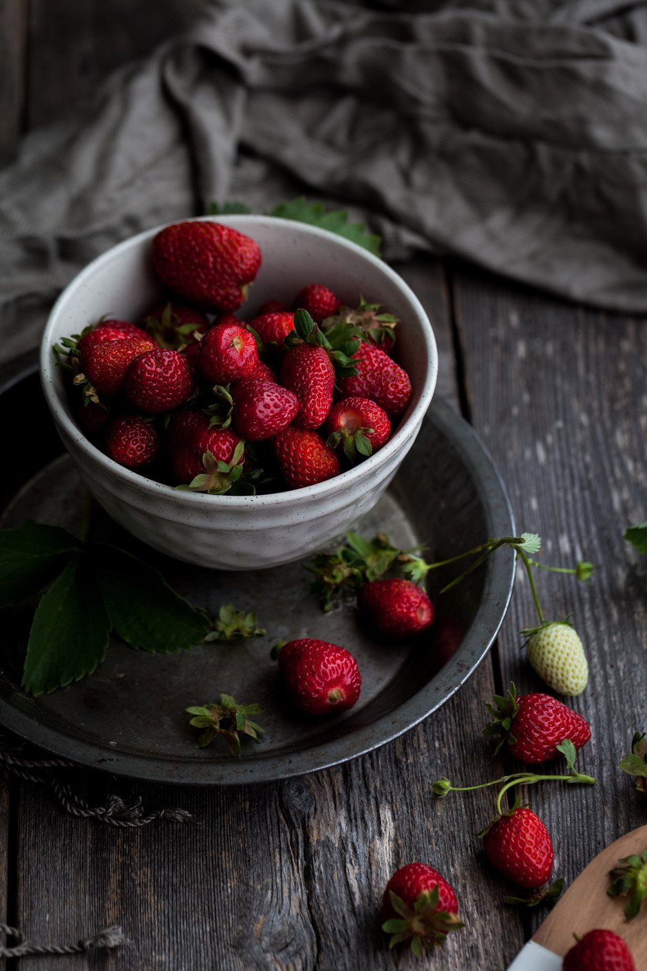 angled closeup view of strawberries in a bowl on a wooden table.