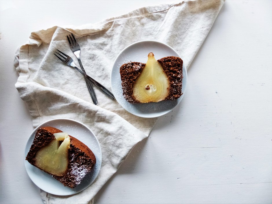 an overhead image of two slices of poached pear gingerbread loaf on a white plates.