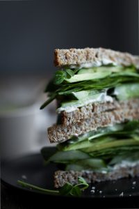 a closeup head on image of a sandwich stacked on a black plate.