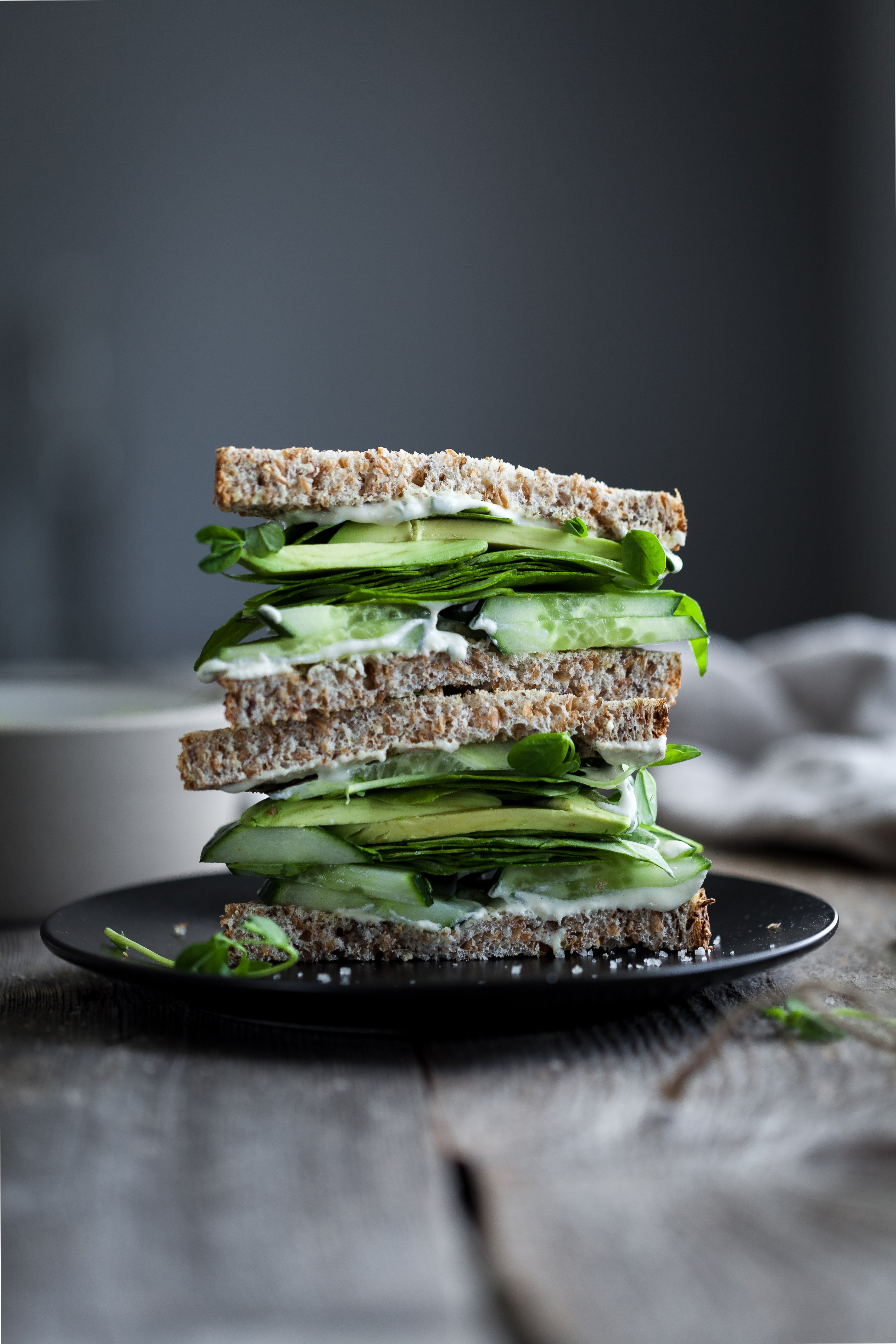 portrait view of a green goddess sandwich stack on a black plate.
