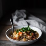 a head on image of a bowl of soup sitting on a wood table.