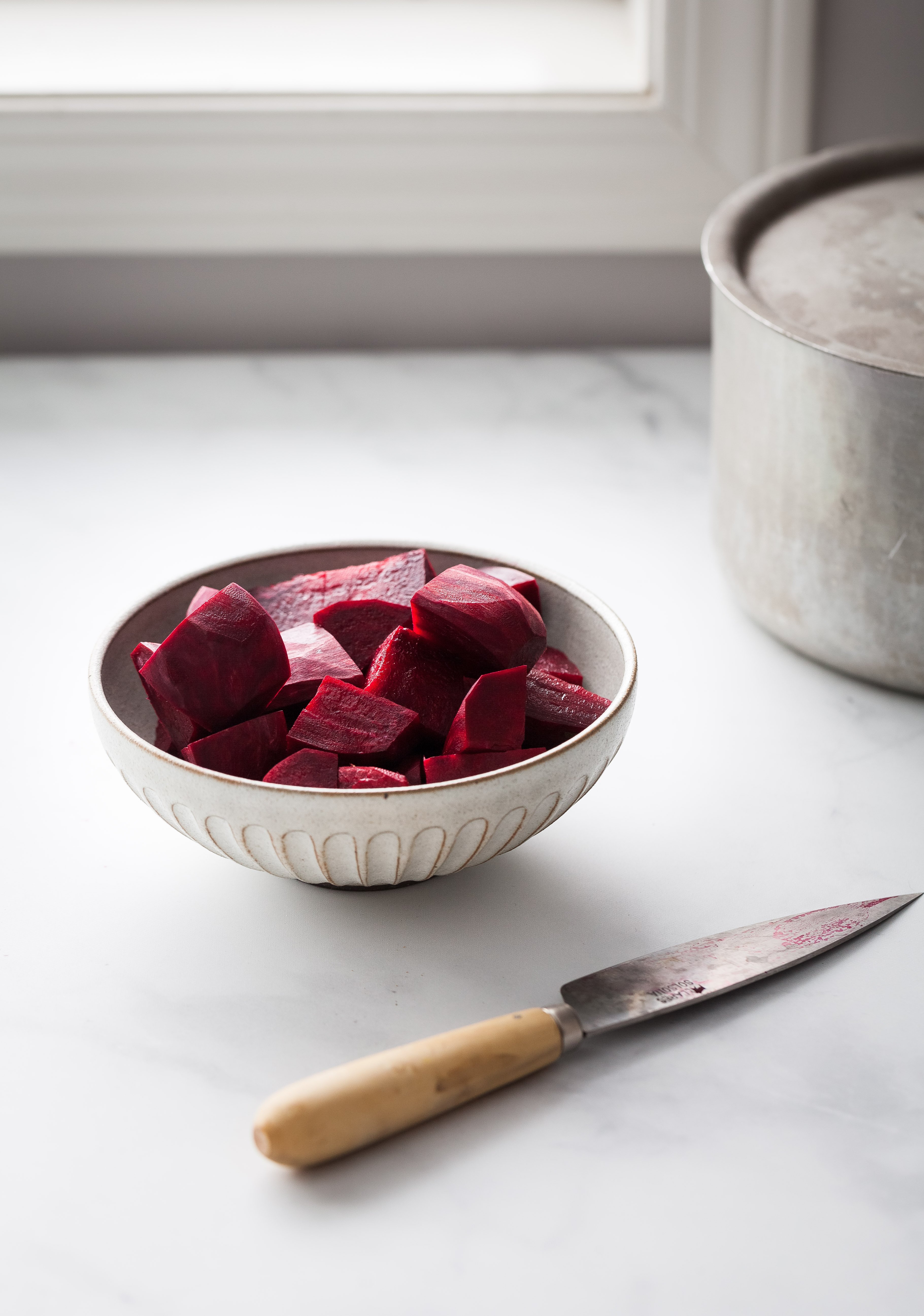a hea don image of cut up beets sitting in a bowl next to a window.