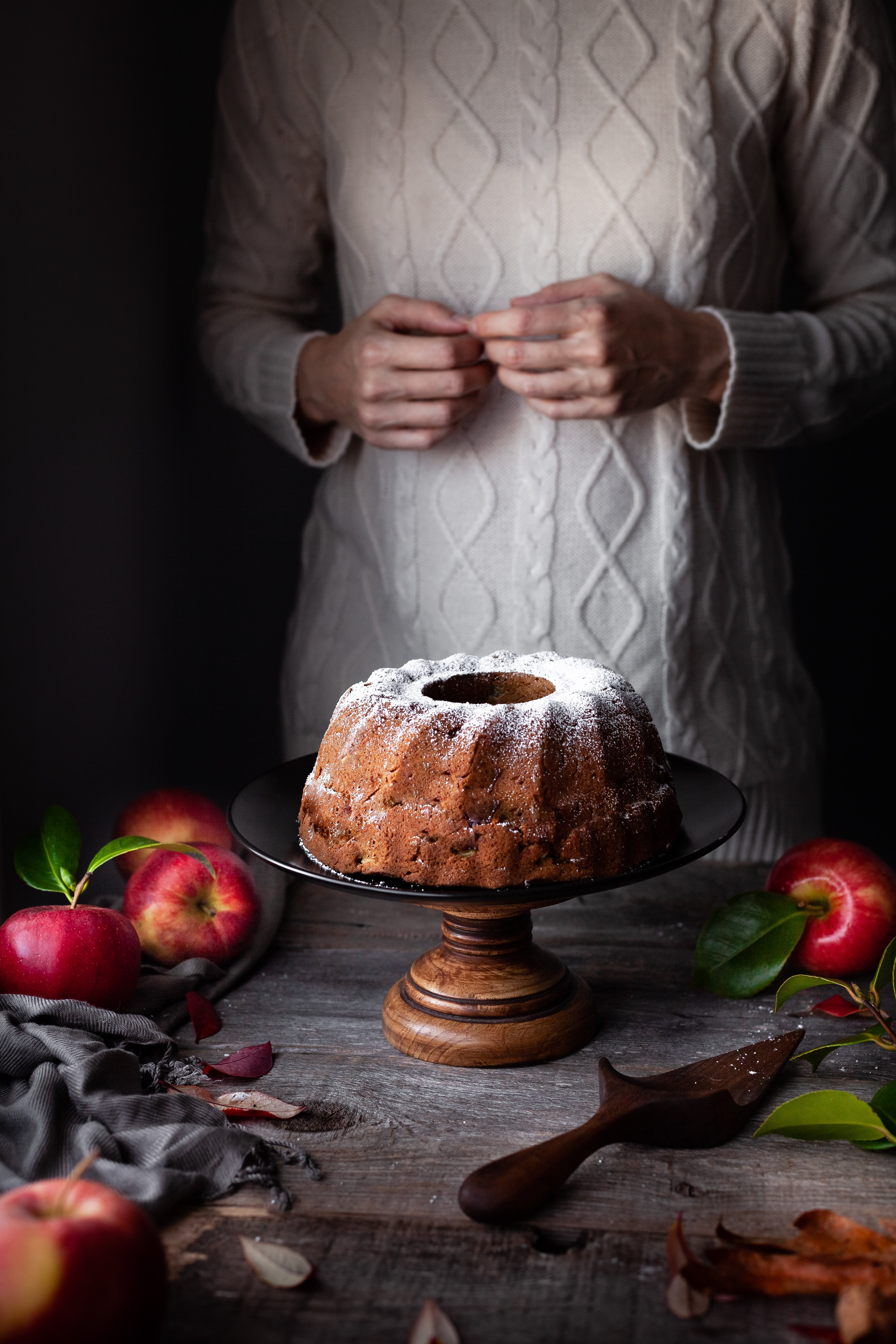 head on image of vegan apple spice cake with bakers hands.