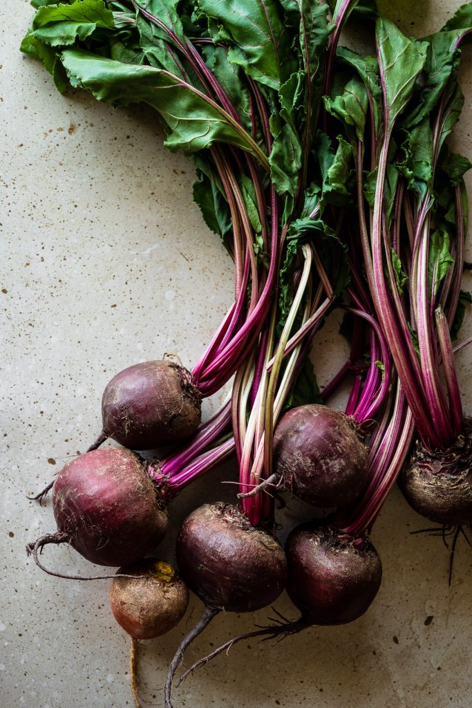 overhead view of whole fresh beets on a stone surface.