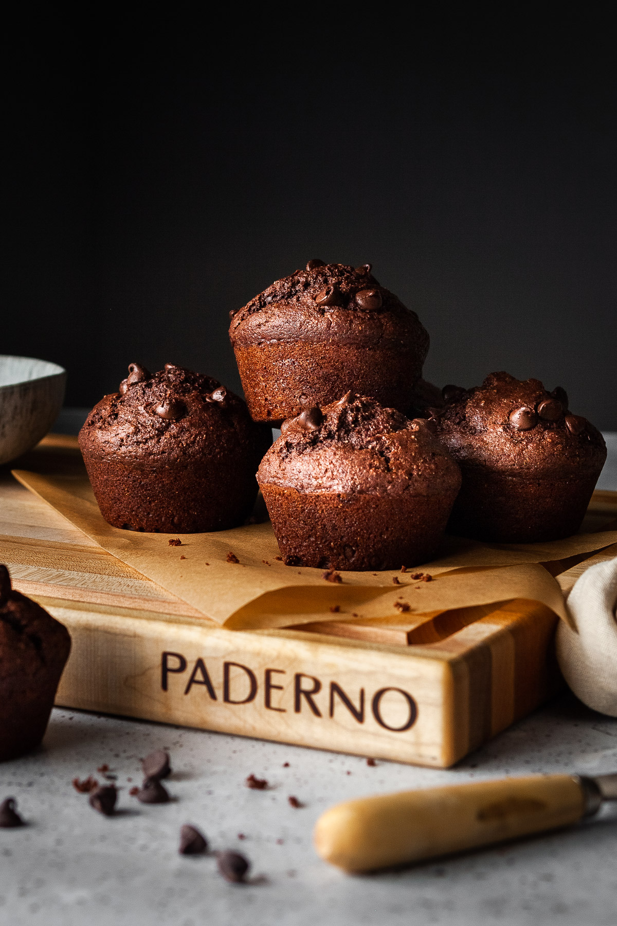 close up of 4 chocolate beet muffins on a cutting board with parchment paper.